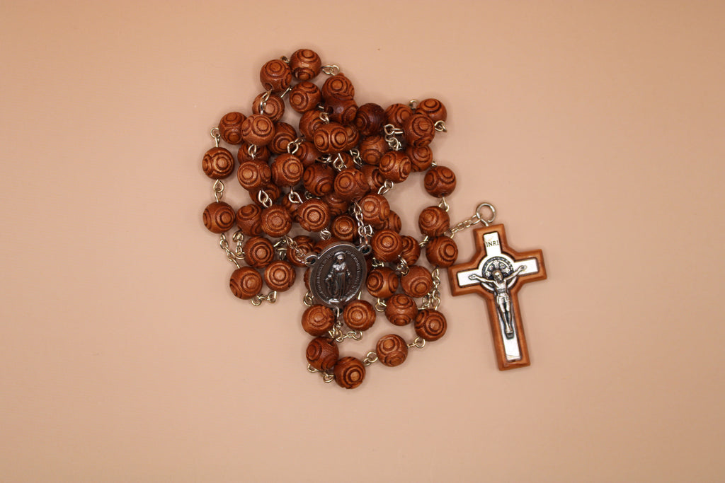 Brown rosary with a cross on a beige background
