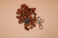 Brown rosary with a cross on a beige background