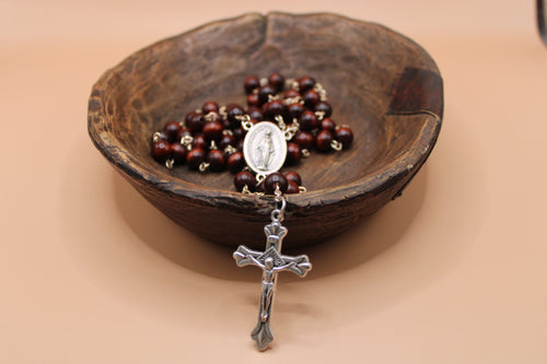 Rosary with a wooden bowl on a beige background