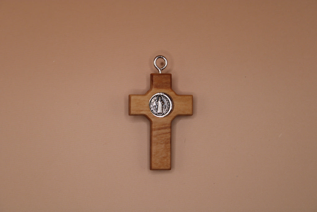 Wooden cross pendant with a St. Benedict seal on a beige background