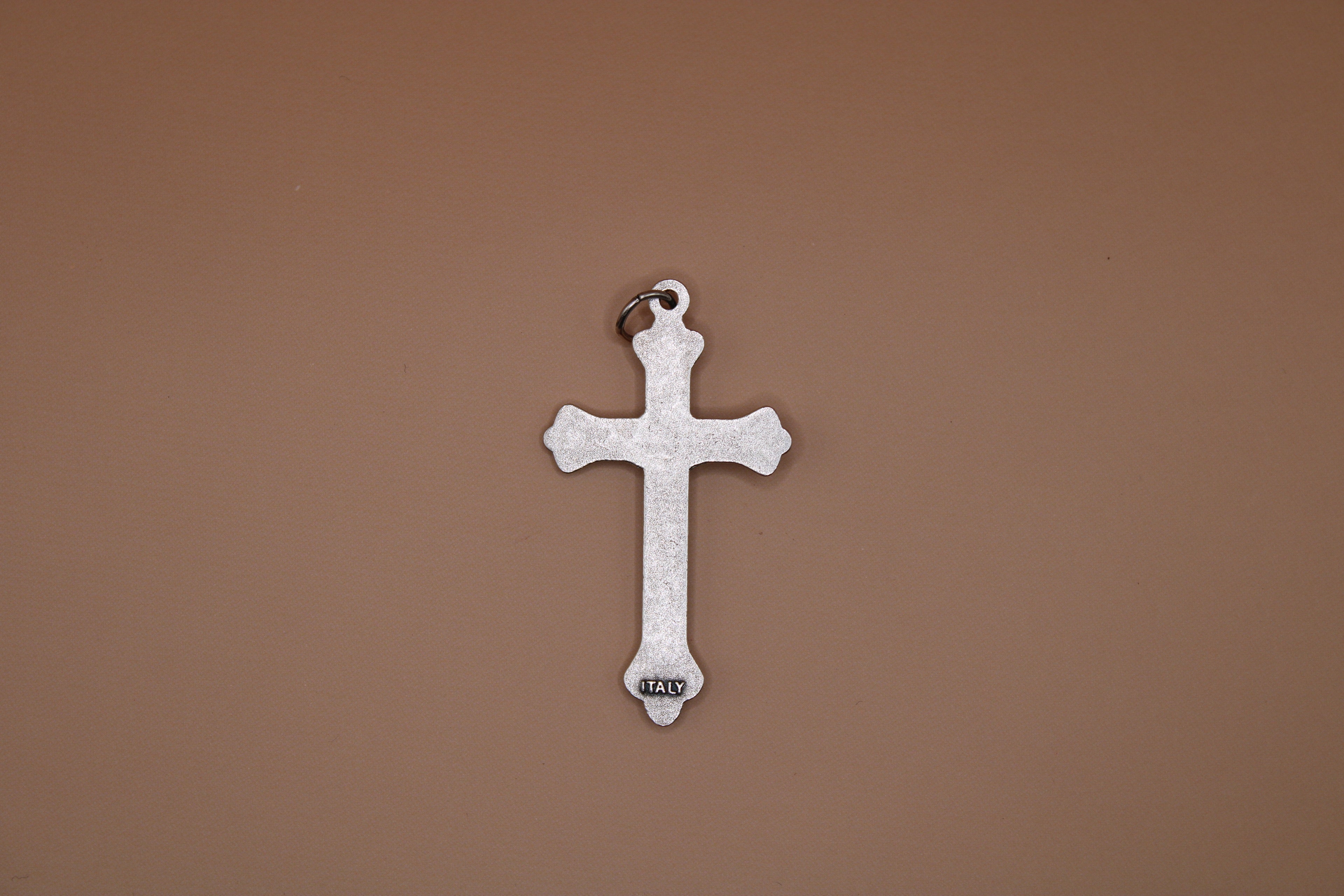 Silver cross pendant on a brown background