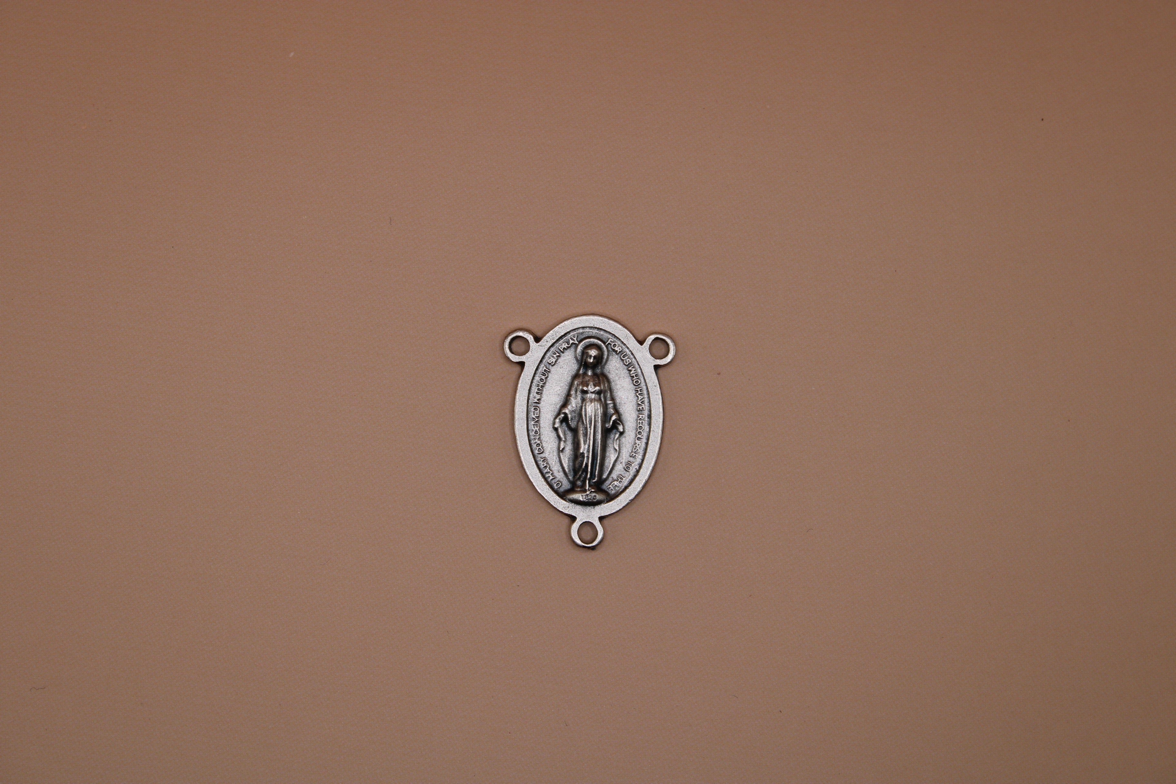 Silver miraculous medal on a brown background