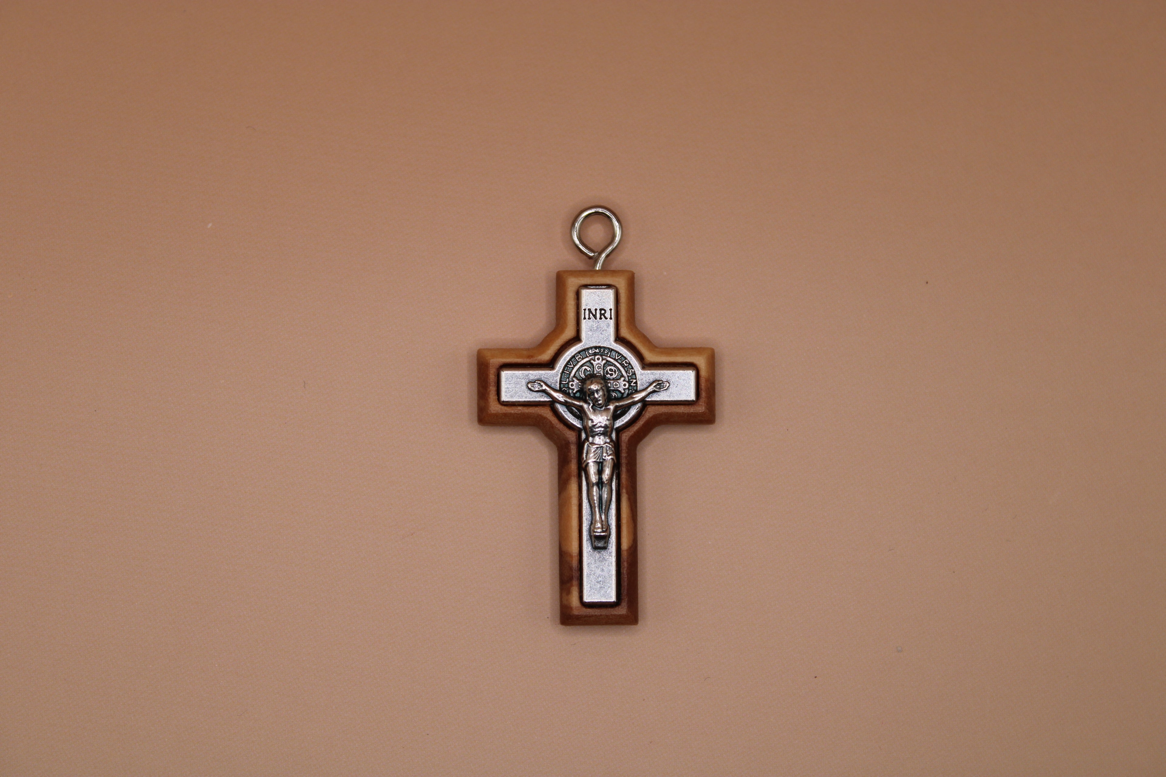 Cross pendant with Jesus Christ figure on a beige background